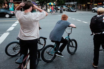 REAR VIEW OF PEOPLE WITH BICYCLE ON STREET