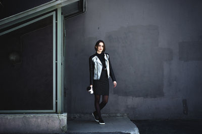 Full length of young woman standing against wall