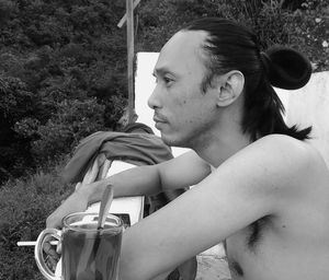 Side view of thoughtful young man leaning by drink on railing