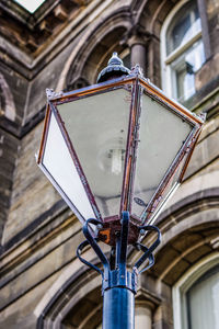 Low angle view of electric lamp hanging on building