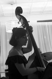 Side view of young woman playing double bass 