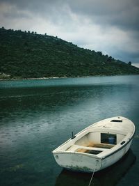 Boat moored on lake against sky