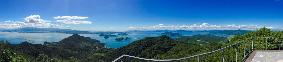 Panoramic view of mountains by sea against blue sky