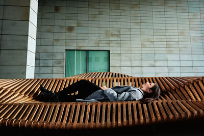 Woman lying on city bench and enjoying sunny summer day