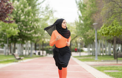 Beautiful woman in headscarf looking away while running in public park