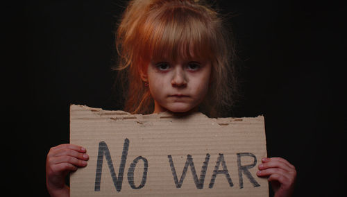 Portrait of girl holding banner against black background