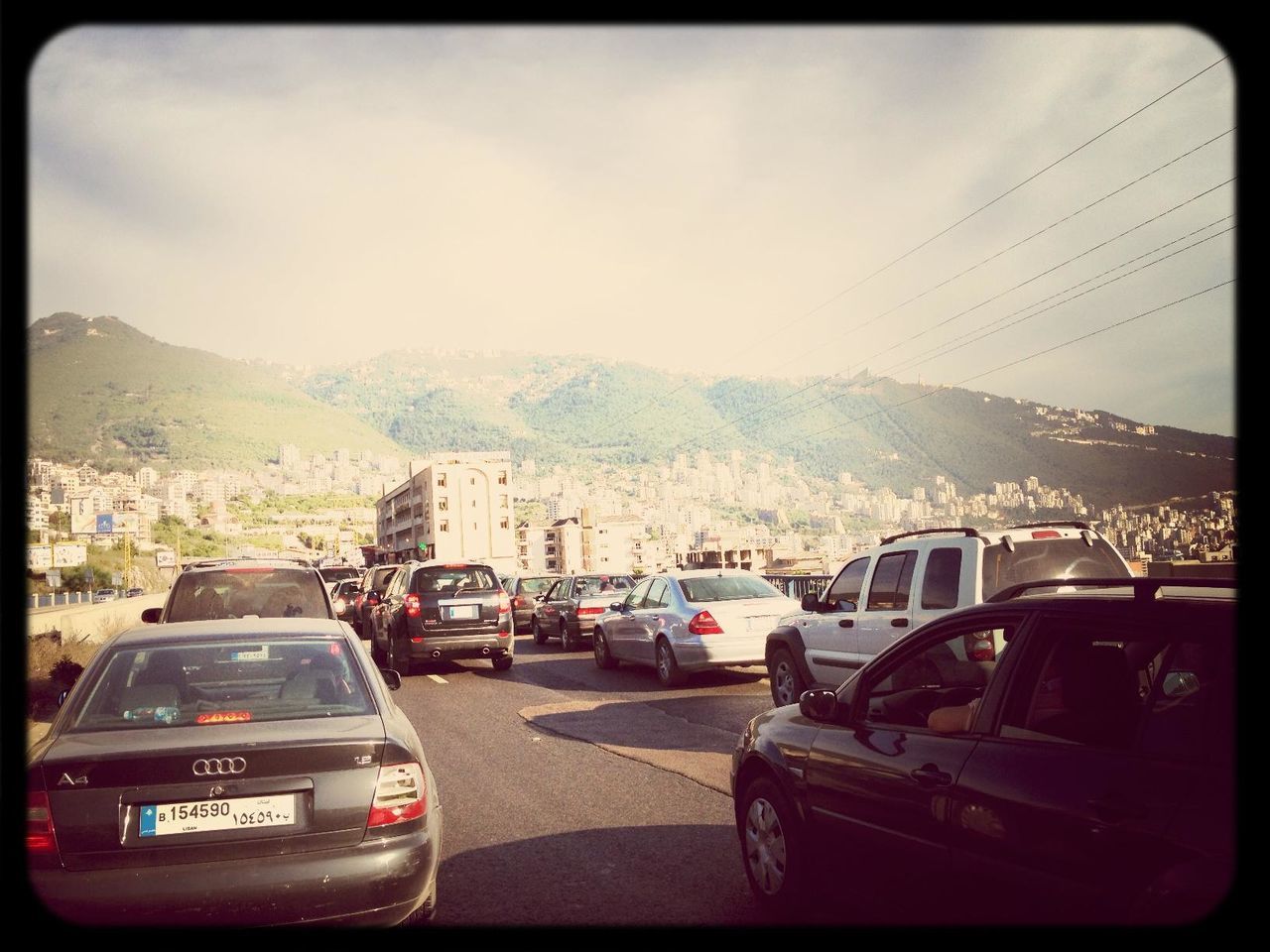 car, transportation, land vehicle, mode of transport, transfer print, sky, mountain, auto post production filter, road, travel, street, vehicle, on the move, traffic, cloud, architecture, built structure, cloud - sky, mountain range, outdoors