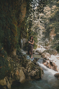 Portrait of woman sitting on swing against waterfall