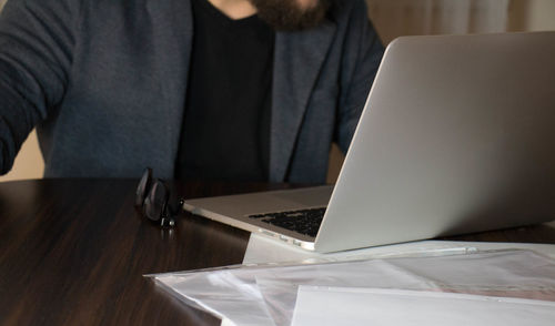 Midsection of man using laptop at table