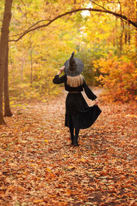 Rear view of woman walking on street during autumn