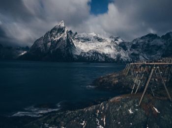 Scenic view of snowcapped mountains by sea against sky