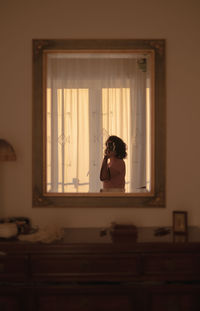 Woman looking through window at home