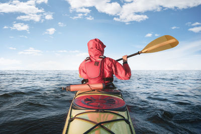 Rear view of man on boat in sea against sky