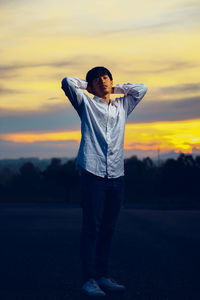 Full length of woman standing on land against sky during sunset