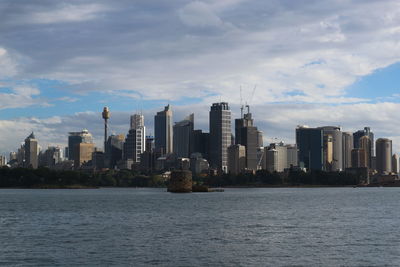 Sea by modern buildings against sky in city