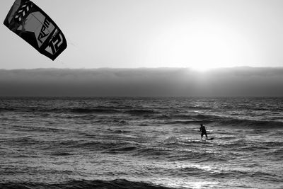 Man kiteboarding in sea against sky