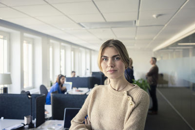 Portrait of young woman standing in office