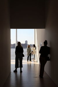 Rear view of silhouette people standing against window