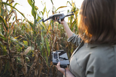 Woman with remote control and drone in maize field
