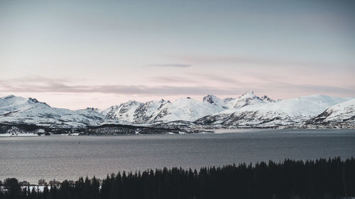 Scenic view of lake against snowcapped mountains during sunset
