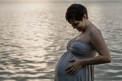 Side view of woman standing against sea