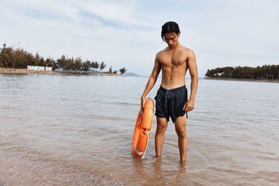 Rear view of shirtless man standing in lake