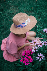 High angle view of woman sitting by pink flowers on field