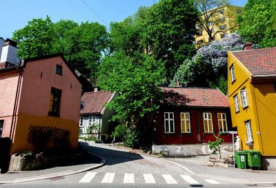 Houses by road amidst trees and buildings against sky