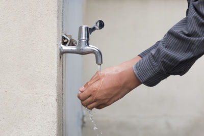 Close-up of hand with faucet in water