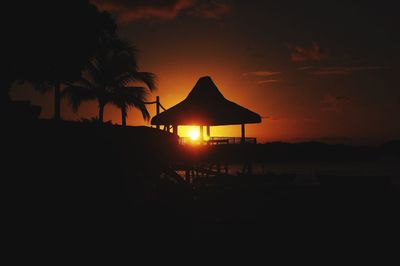 Silhouette trees on beach against sky during sunset