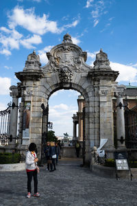 Woman walking against arched built structure