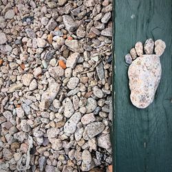 High angle view of footprint made from stones on wooden bench