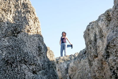 Woman standing on rock against clear sky