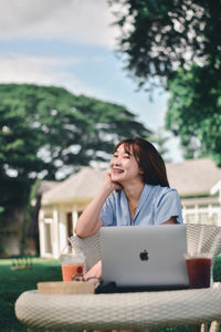 Woman using phone while sitting on table