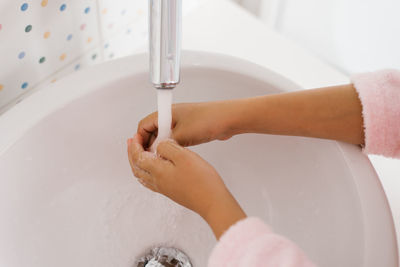 Close up view of young child washing hands with soap in sink