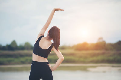 Girl exercising against sky