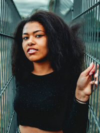 Portrait of beautiful woman standing by fence