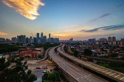 Distant view of petronas towers against sky during sunset in city