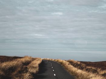 Road amidst land against sky