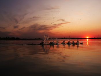 Silhouette boats in sea against sky during sunset