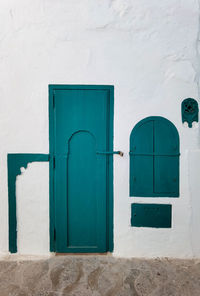 Turquoise wooden door with a window in the old medina of asilah