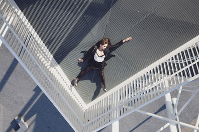 High angle view of young woman lying down on elevated walkway