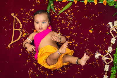 Cute indian boy dresses as lord rama with bow and flowers from top angle