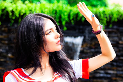 Portrait of young woman with arms raised standing outdoors