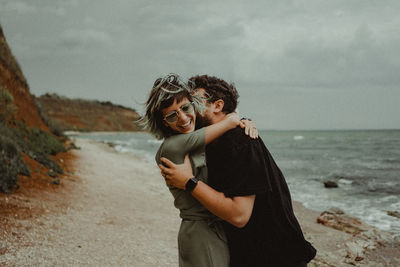 Couple standing at beach against sky