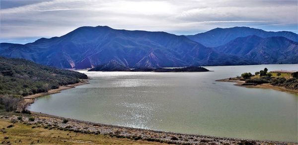 Scenic view of lake by mountains against sky