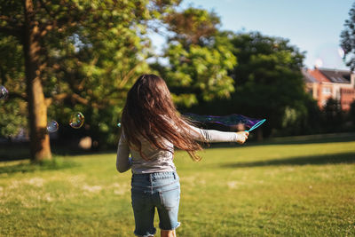 Portrait of a beautiful caucasian girl blows soap bubbles standing in the park