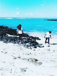 Rear view of friends standing at beach