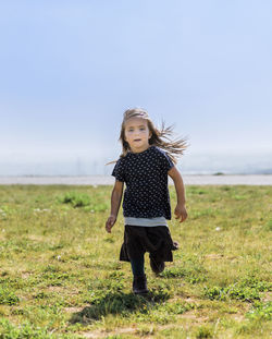 Full length of girl running on grass against sky