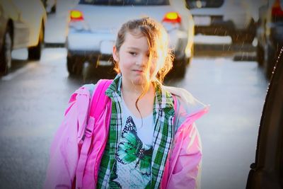 Girl looking at camera while standing by car